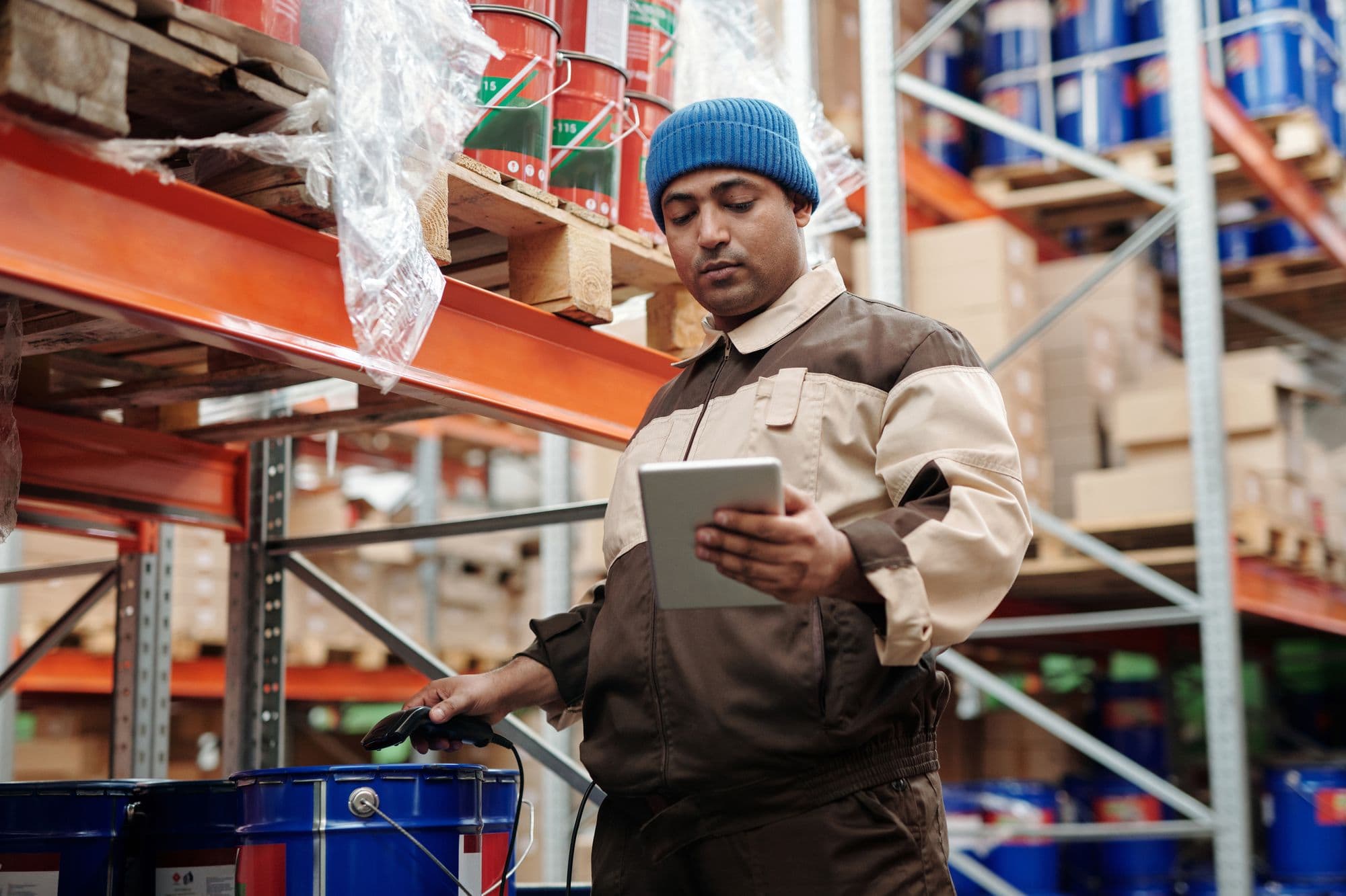 A warehouse worker checking incoming stock on a tablet at the racking