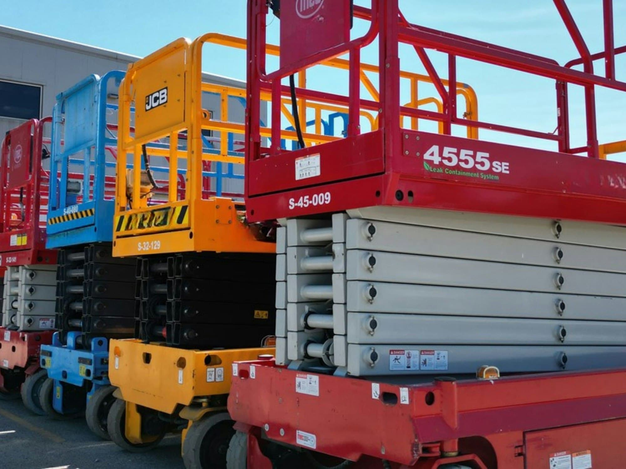 A row of scissor lifts in a hire yard, waiting to go out