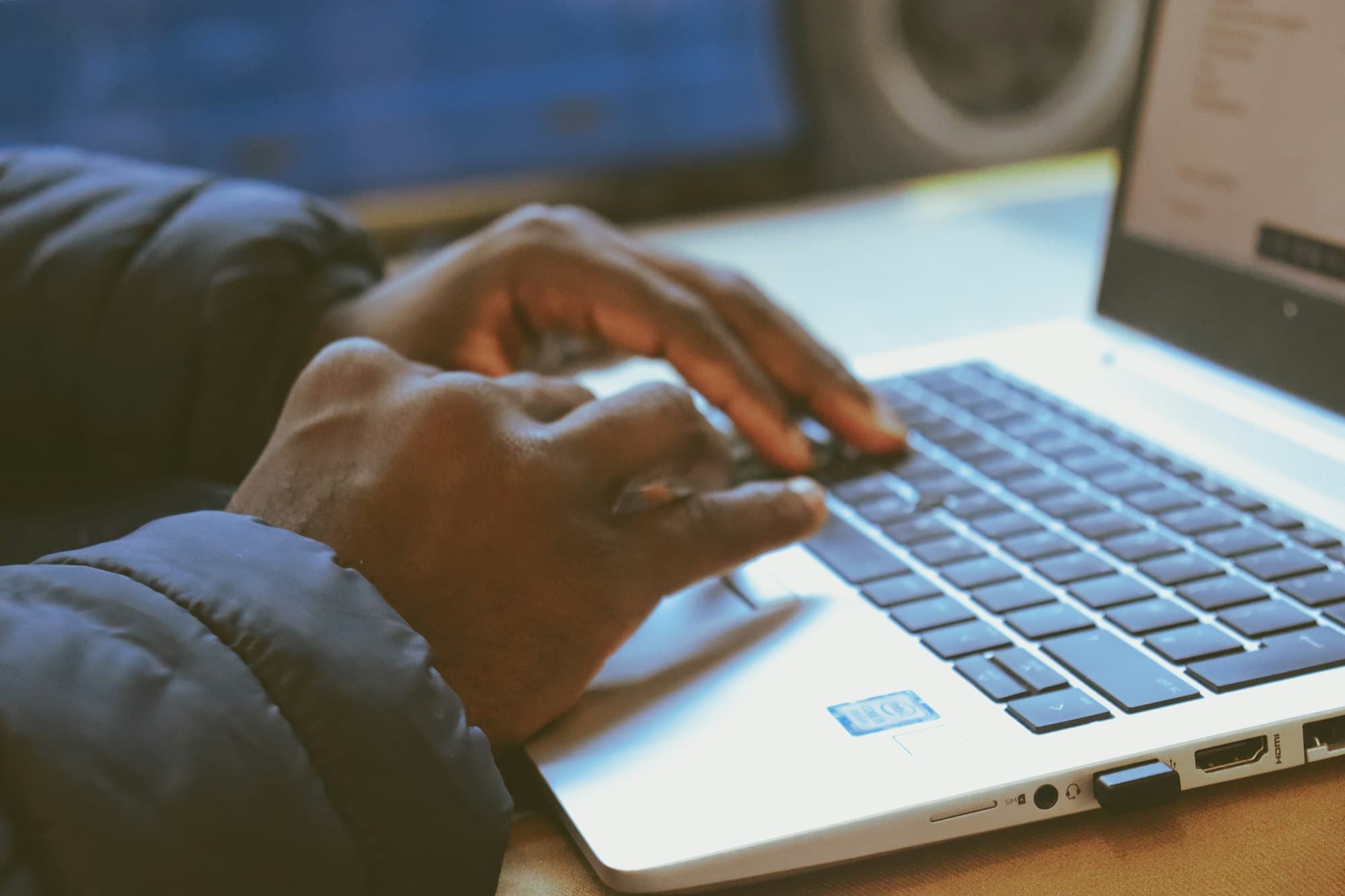 Hands typing on a laptop, a spreadsheet open on the screen