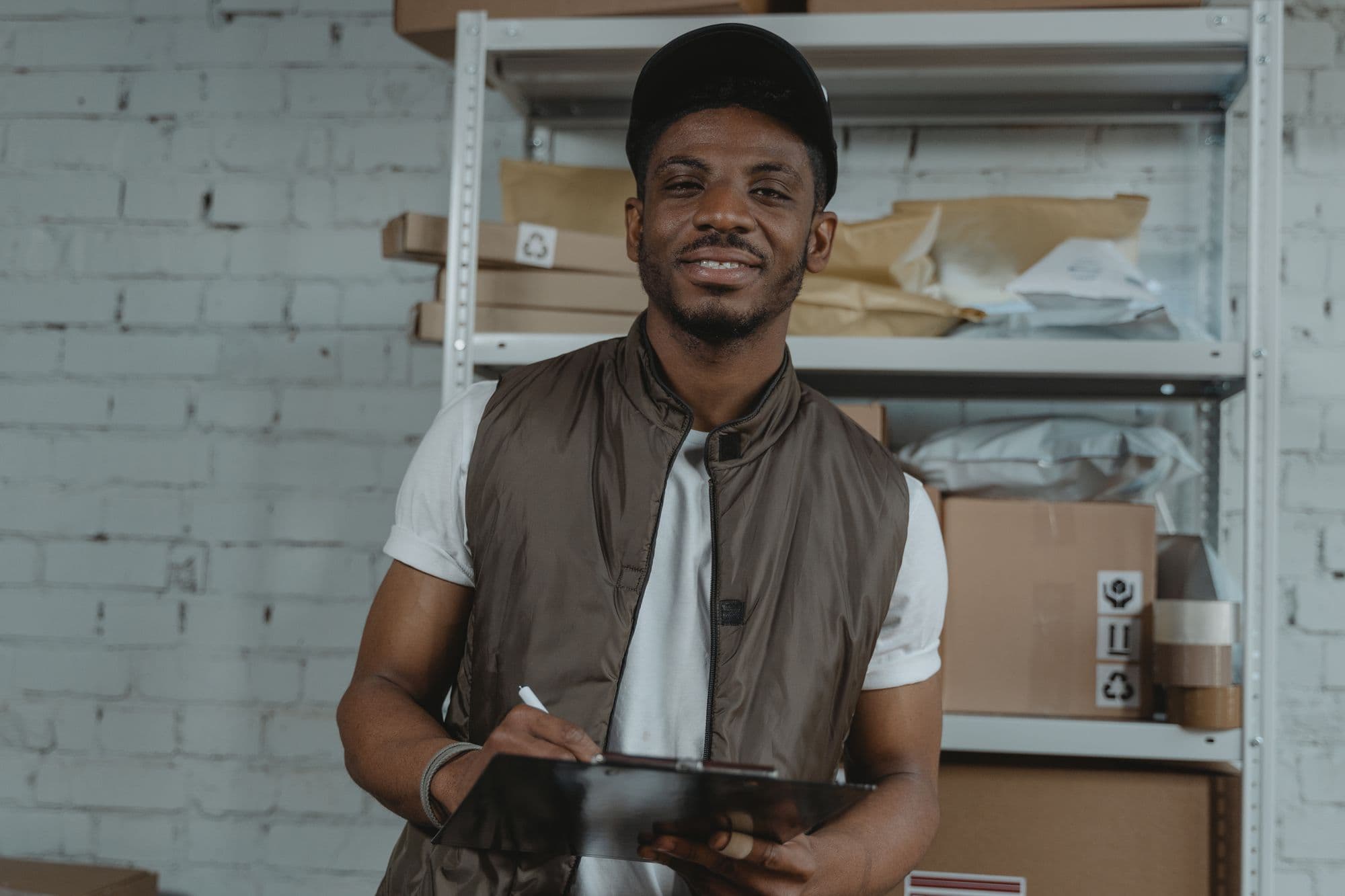 A stockroom worker in an apron counting stock on a clipboard