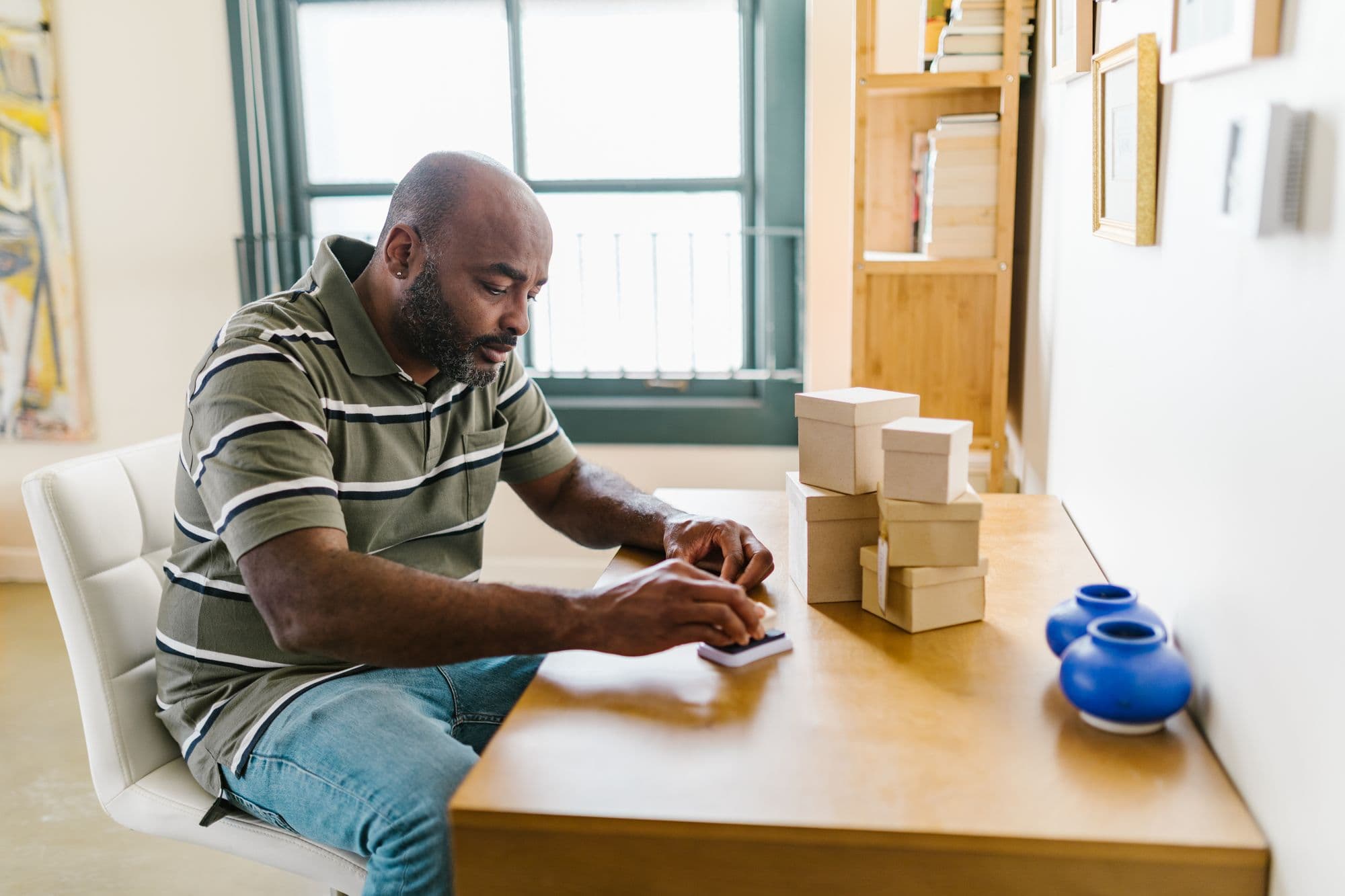 A man packing parcels for dispatch at a table by the window